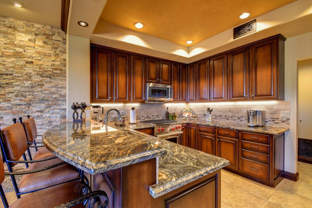 A kitchen with granite counter tops and wooden cabinets.
