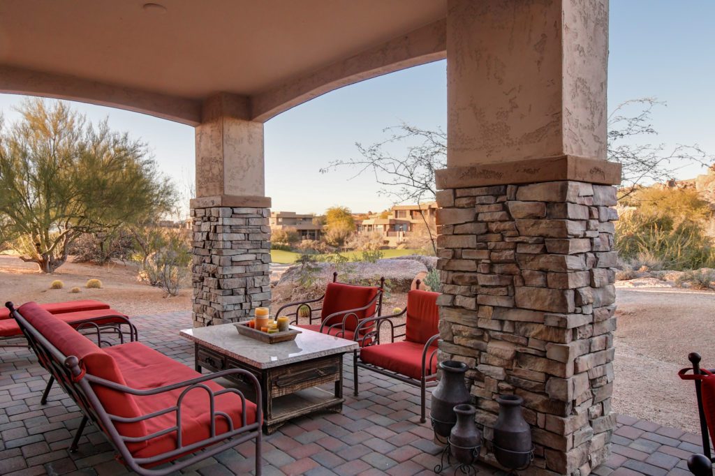A patio with red chairs and tables in the middle of it.