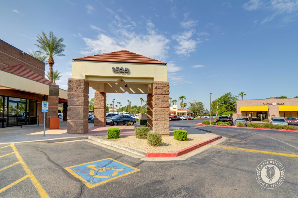 A parking lot with a building and trees in the background.