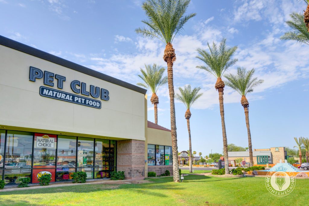 A store front with palm trees in the background.