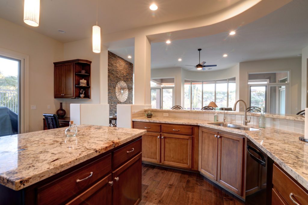 A kitchen with wooden cabinets and marble counter tops.