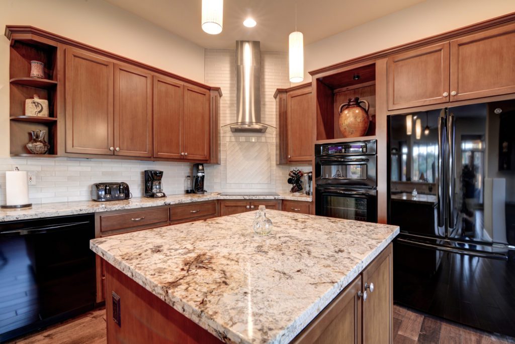 A kitchen with brown cabinets and black appliances.