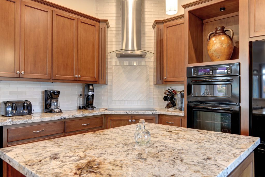 A kitchen with granite counter tops and wooden cabinets.