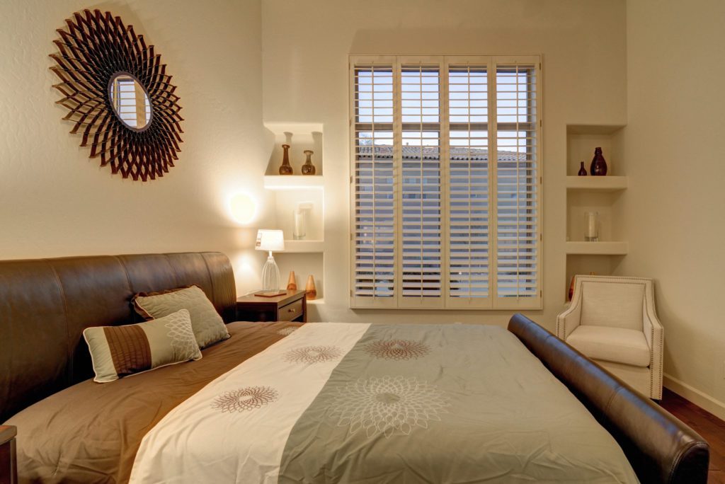 A bedroom with a bed, nightstand and window.