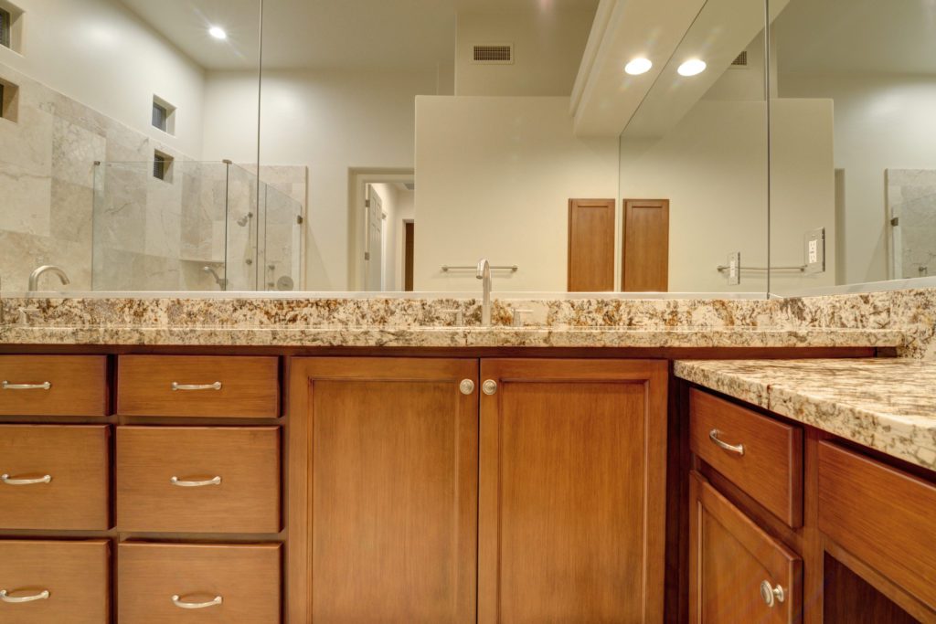 A bathroom with a large mirror and wooden cabinets.