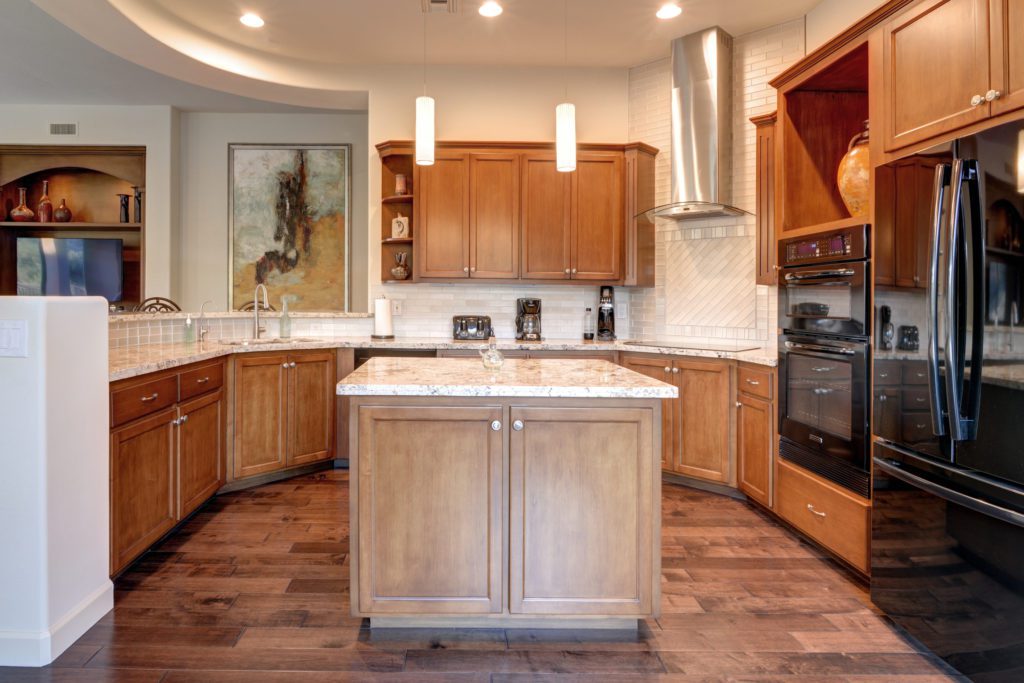 A kitchen with wood cabinets and white counter tops.