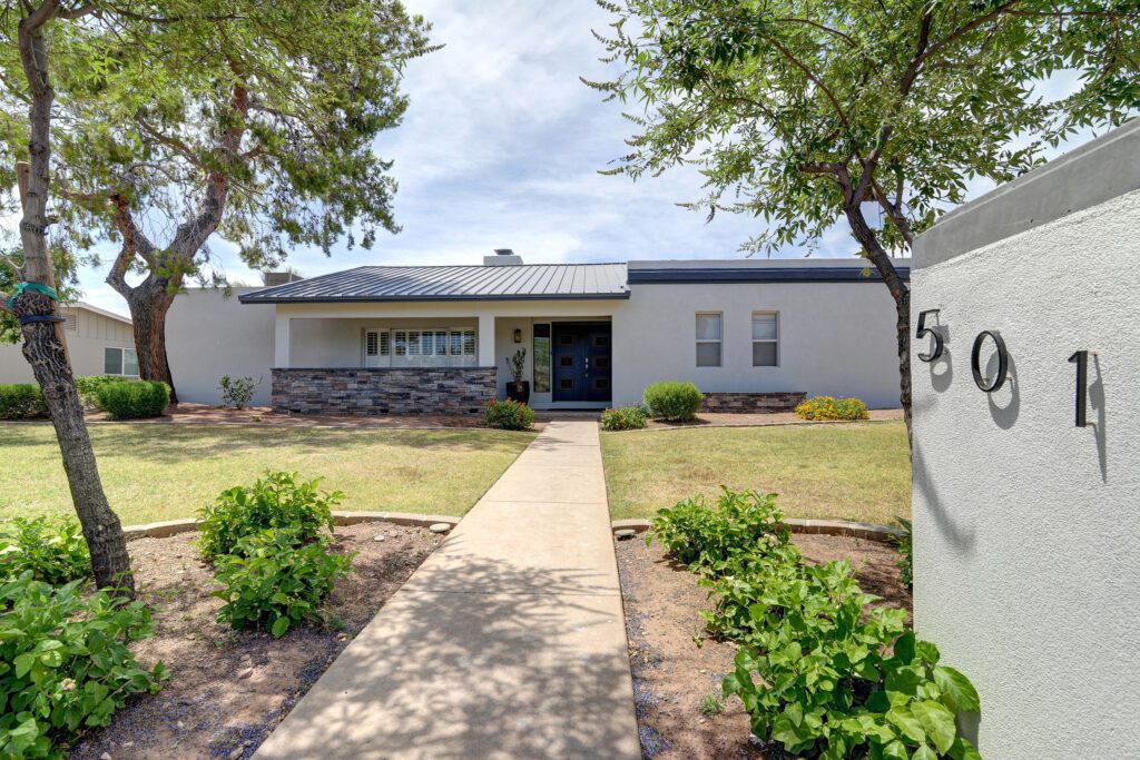A house with a sidewalk and trees in front of it