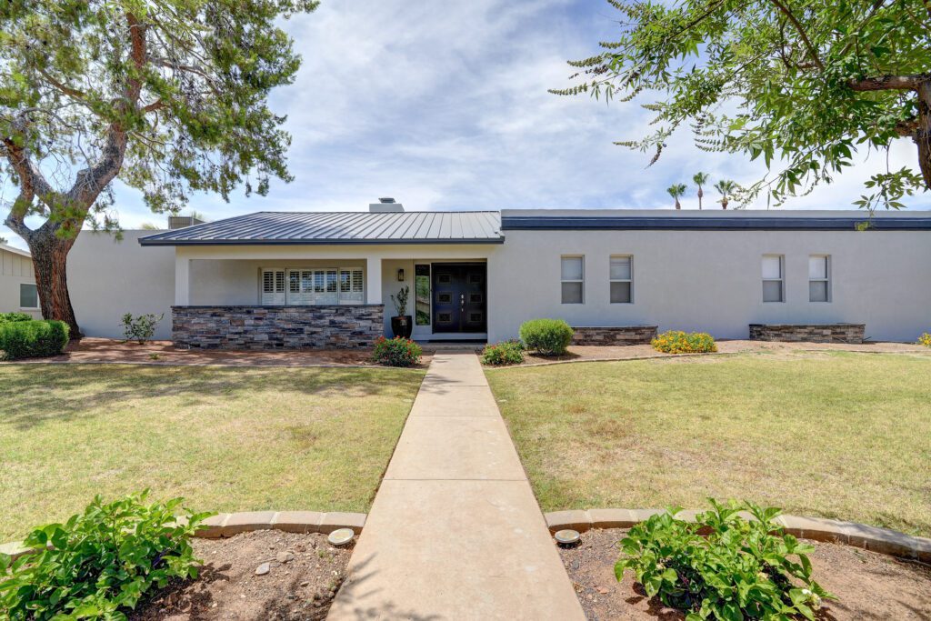 A house with a walkway and bushes in front of it