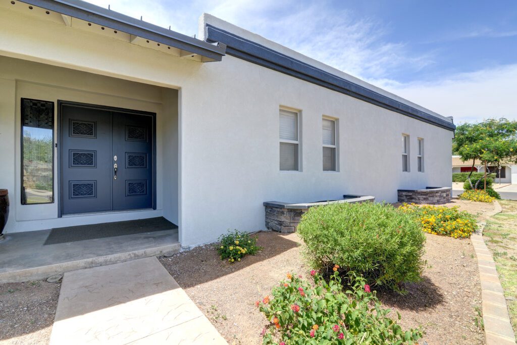 A building with two doors and bushes in front of it.