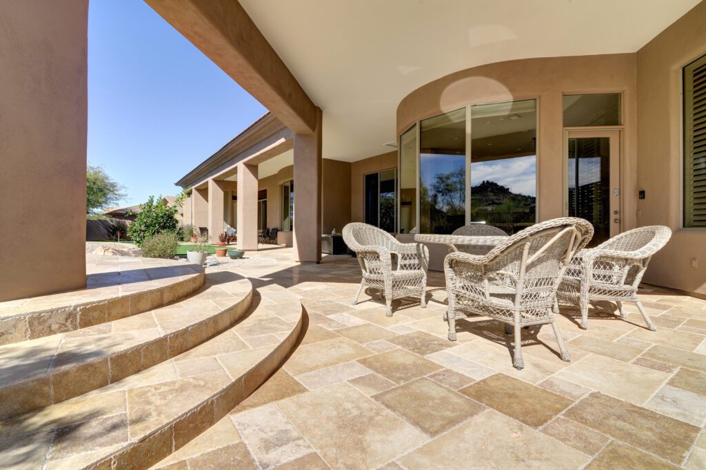 A patio with chairs and tables outside of the house