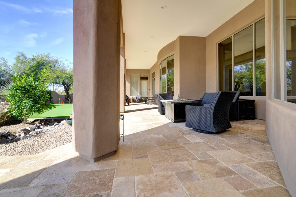 A patio with chairs and tables outside of it