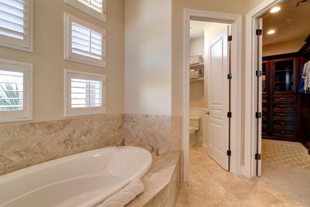 A bathroom with marble walls and floors, and a tub.