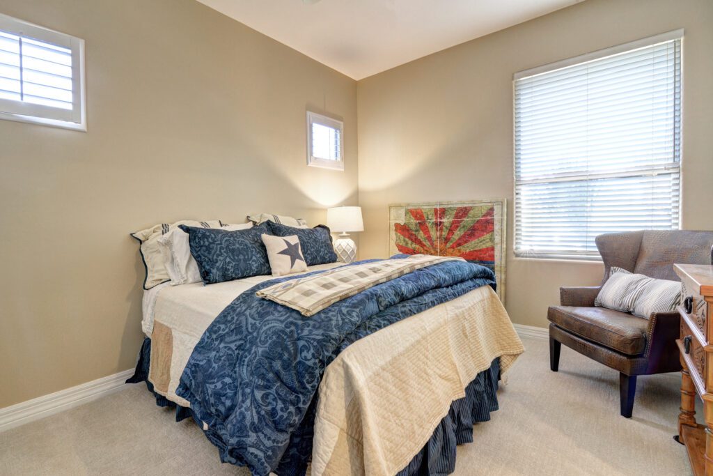 A bedroom with a bed, chair and window.