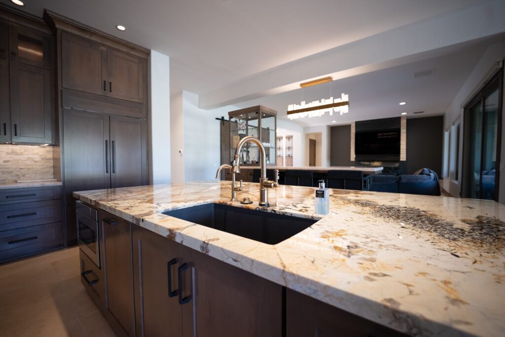 A kitchen with marble counter tops and black sink.