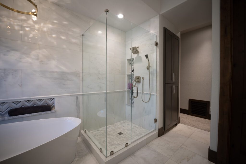 A bathroom with a large glass shower and a tub.
