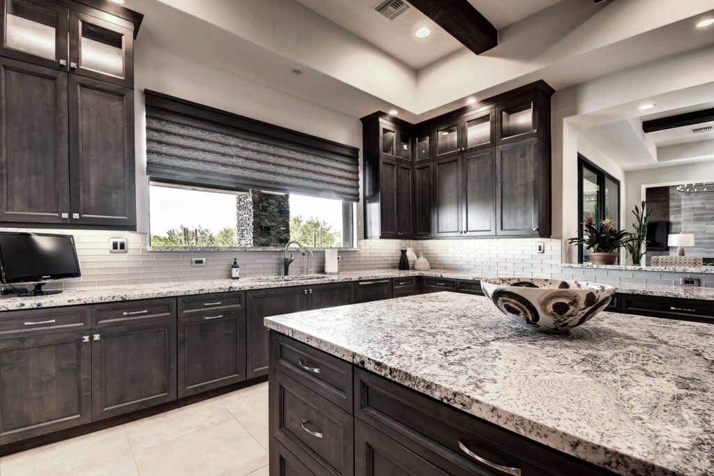 A kitchen with black cabinets and white counter tops.
