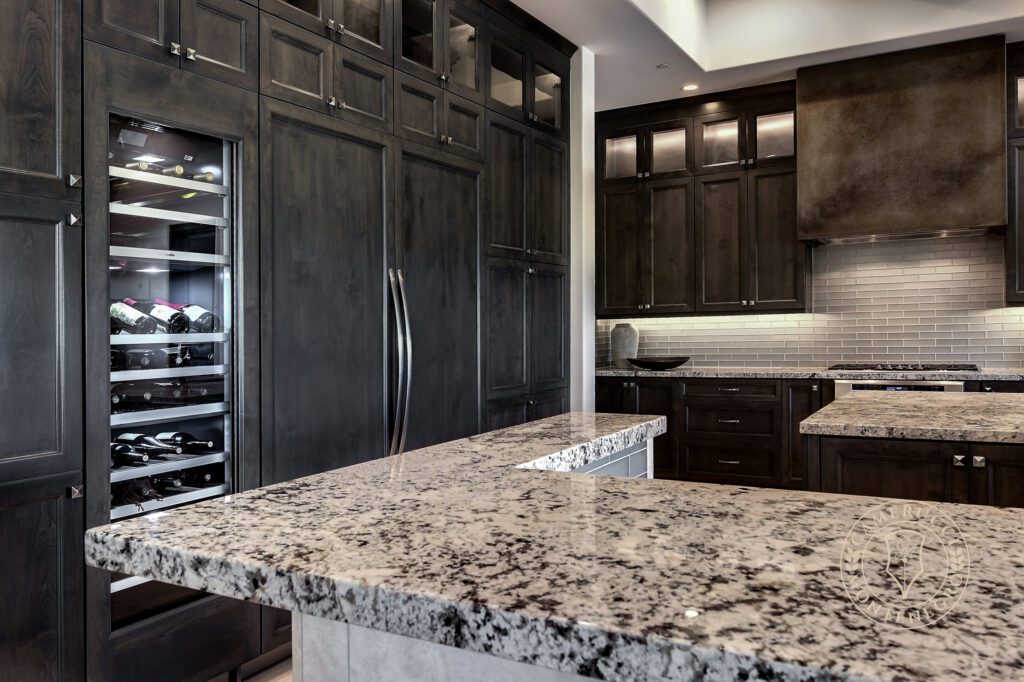 A kitchen with granite counter tops and dark cabinets.