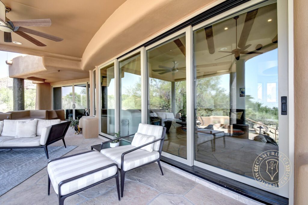 A patio with chairs and tables outside of it