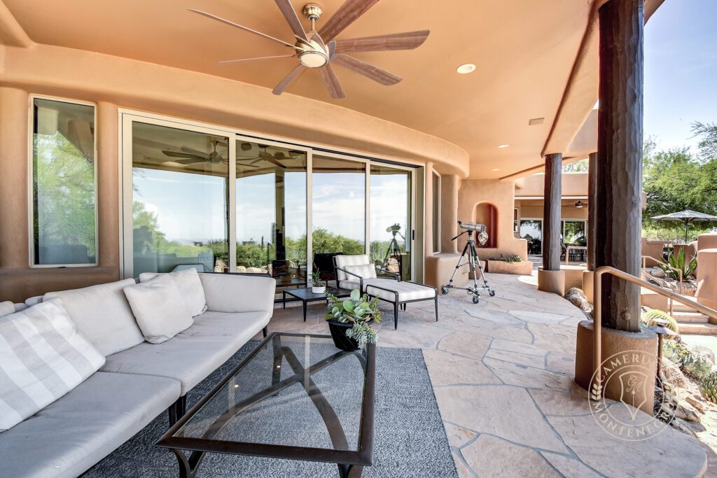 A patio with a couch, table and sliding glass doors.