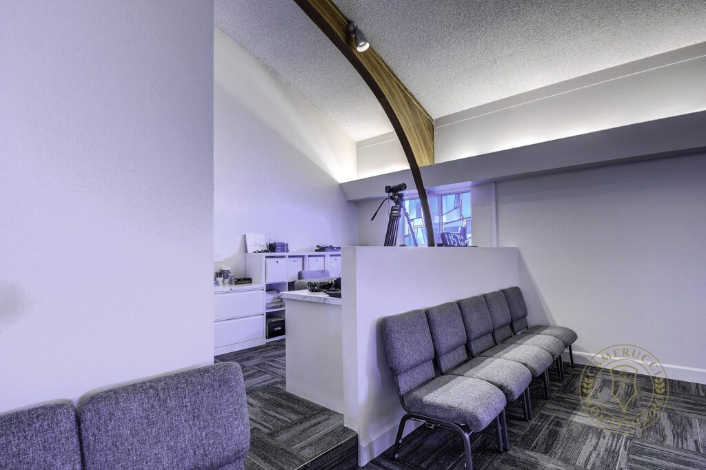 A room with several grey chairs and a white wall.