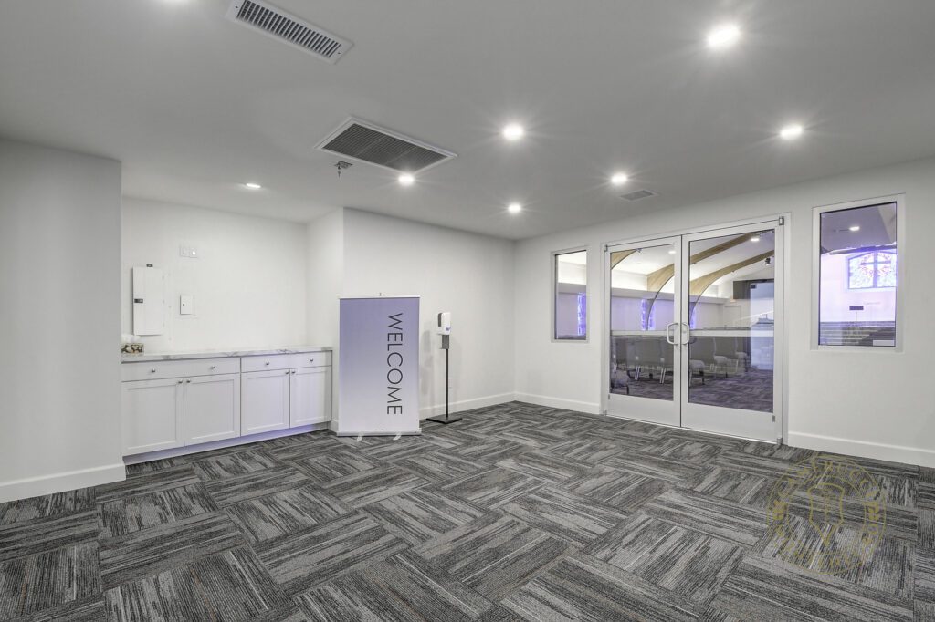 A room with white walls and grey carpet.